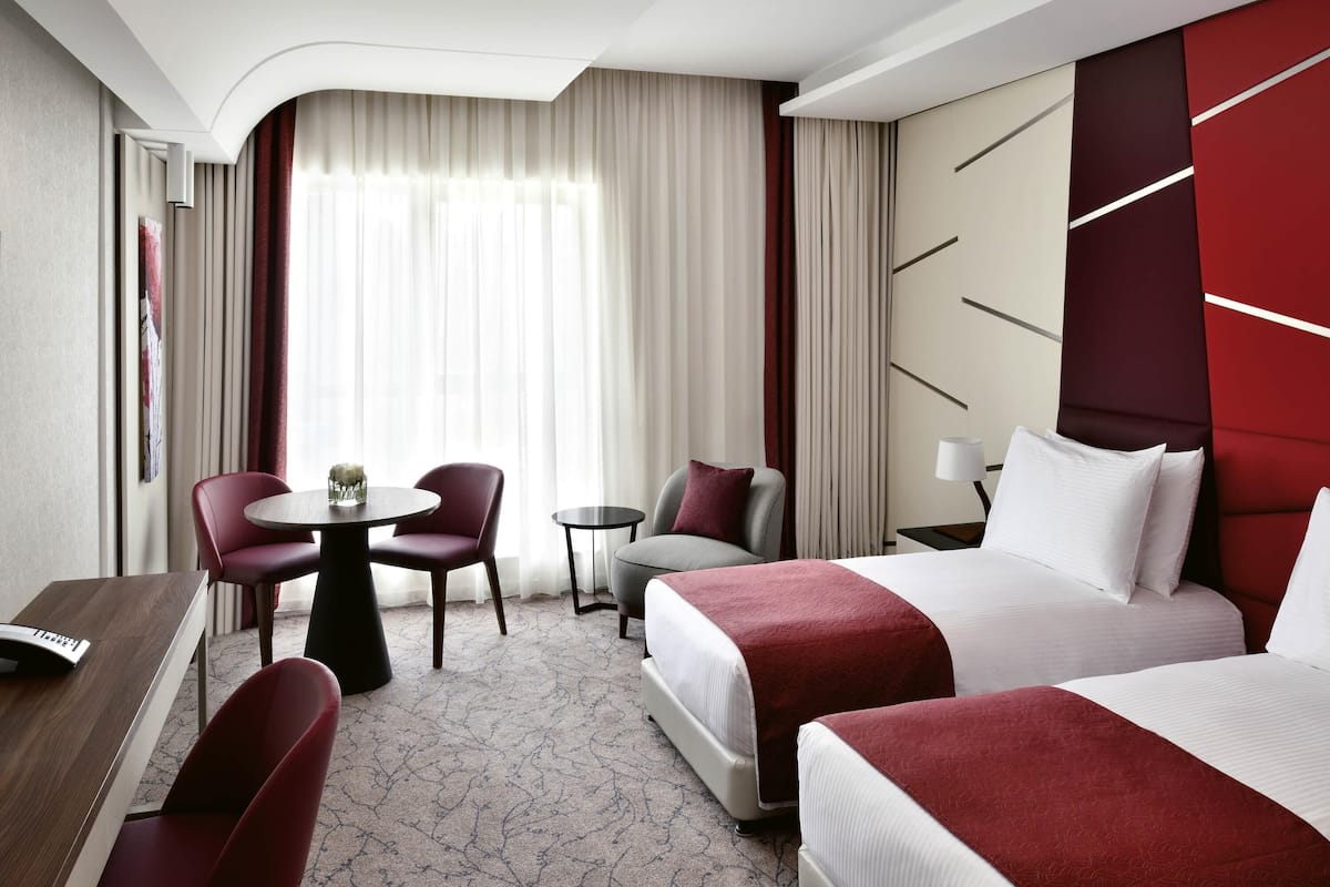 Ein Hotelzimmer mit einem Bett, zwei Stühlen, einem kleinen Tisch und einem Schreibtisch.