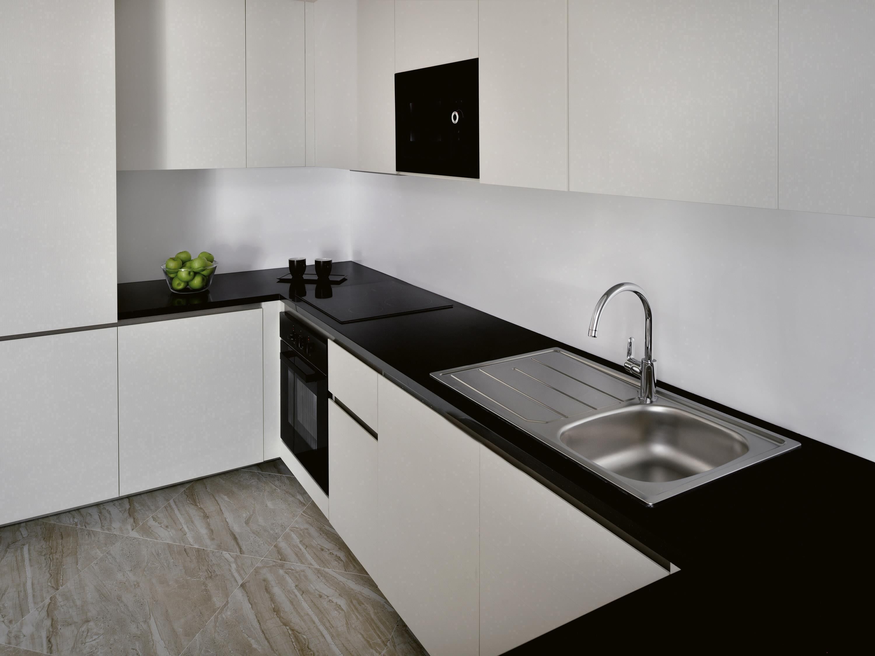 A modern kitchen with a black countertop, stainless steel sink, and white cabinetry.