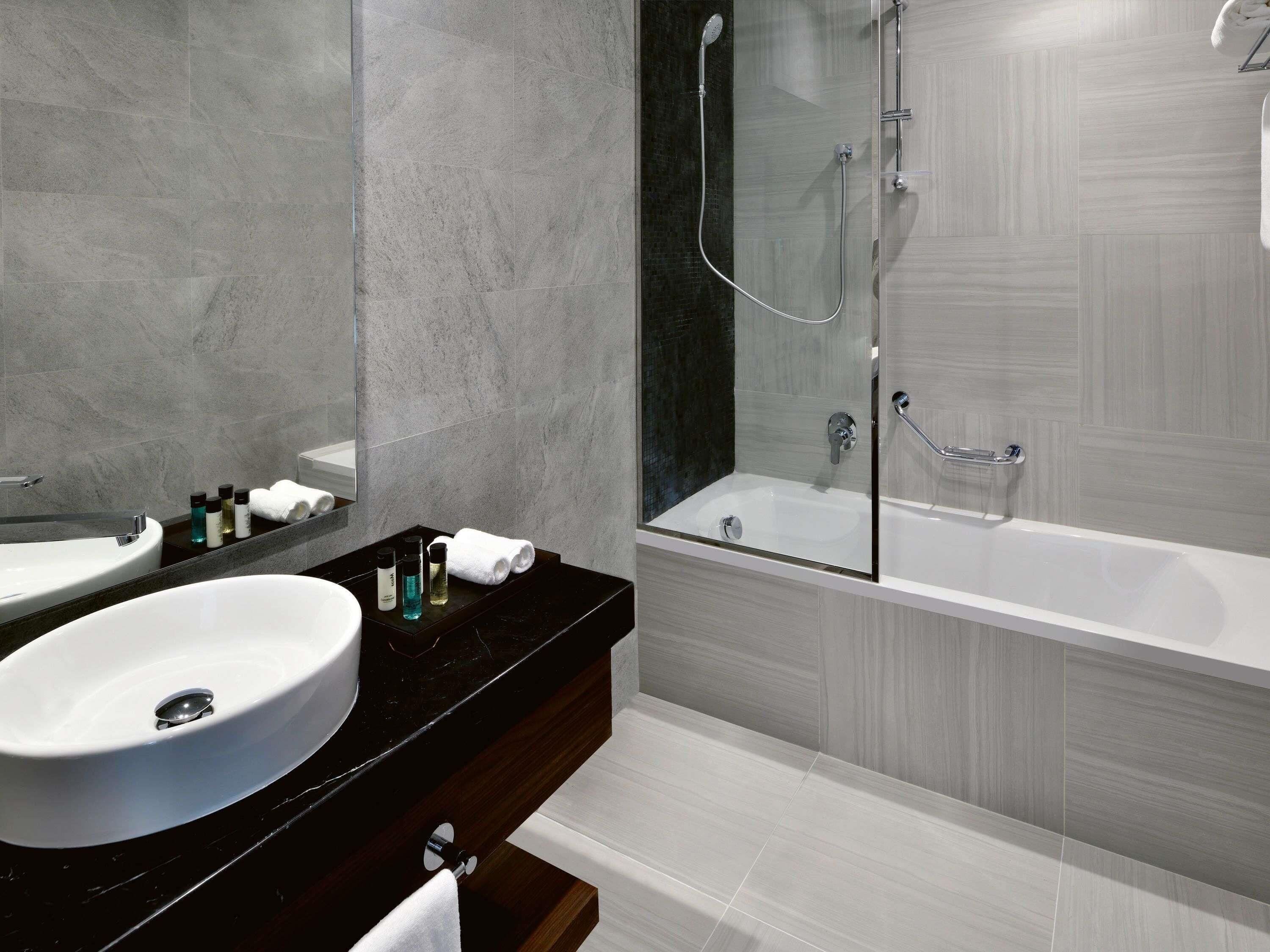 A modern bathroom with a large sink, a mirror, and a glass-enclosed shower area.