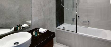 A modern bathroom with a large sink, a mirror, and a glass-enclosed shower area.