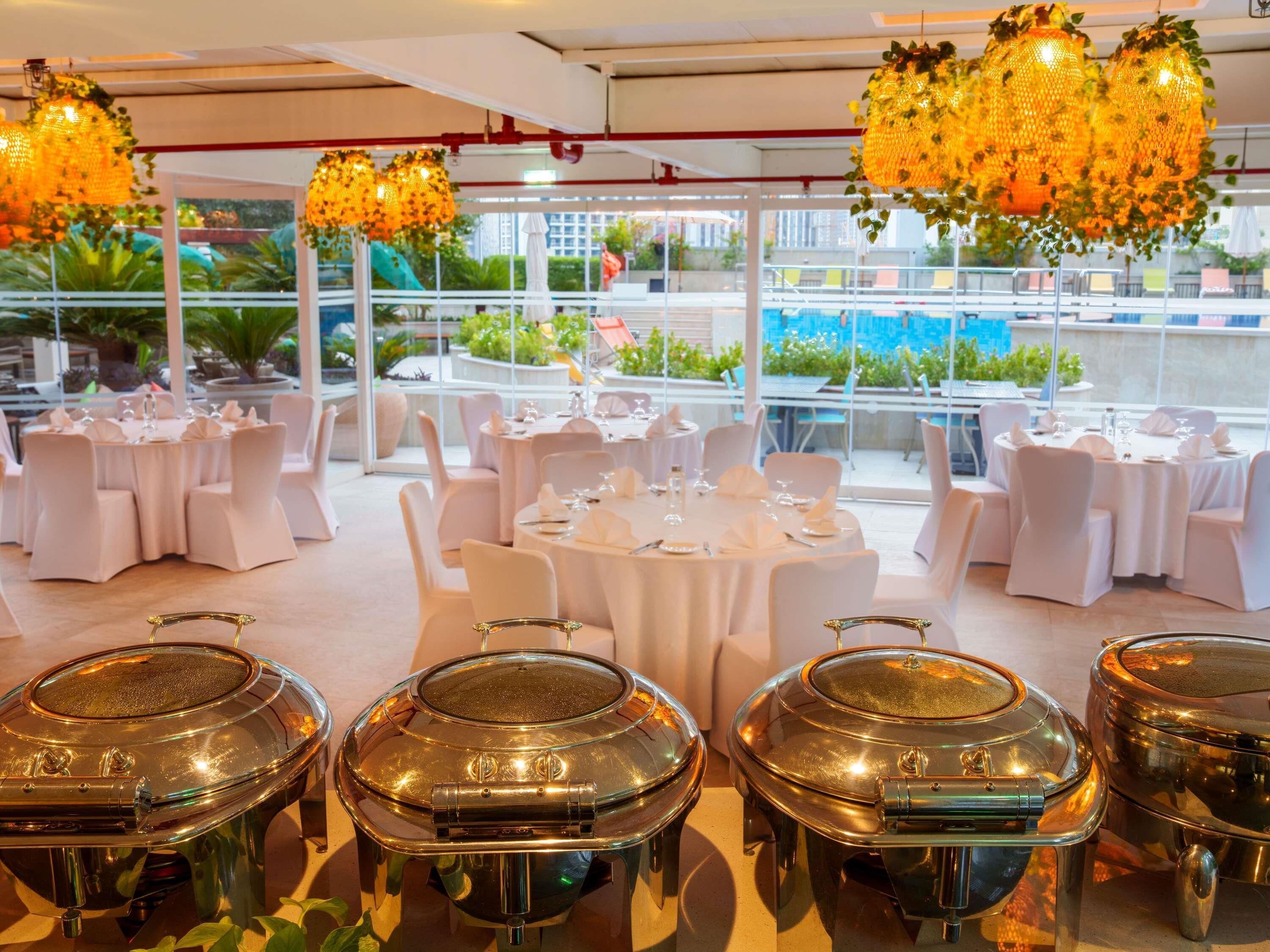 A restaurant with round tables, white chairs, and hanging floral chandeliers.
