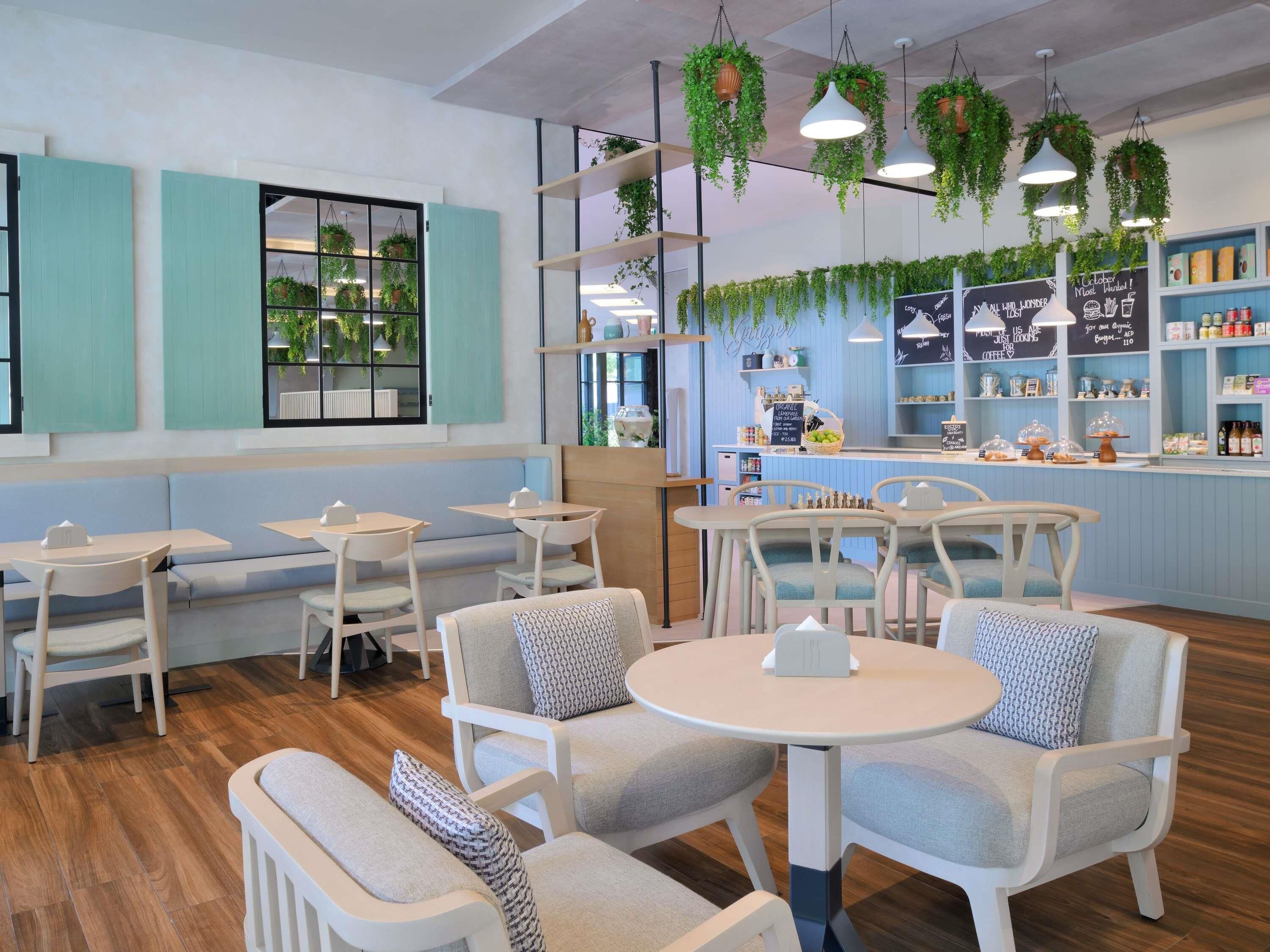 A cafe with seating arrangements, hanging plants, and a counter with various items.