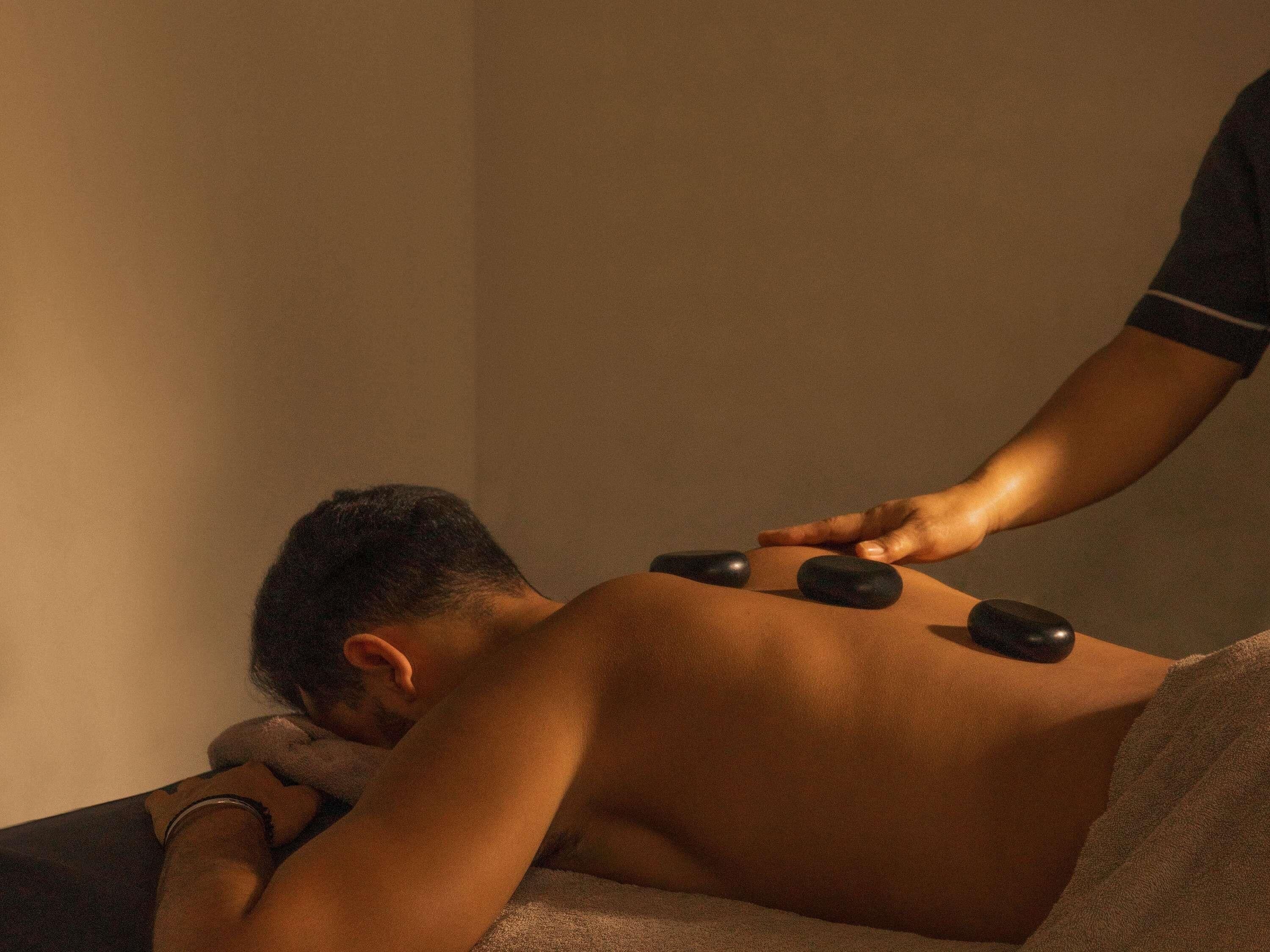 A person receiving a back massage with stones.