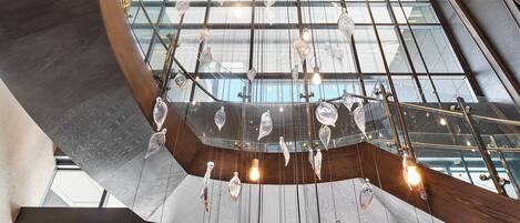 A modern interior with a glass ceiling, wooden beams, and hanging light fixtures.