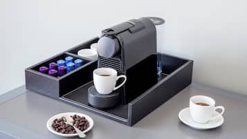 Una cafetera con una bandeja, tazas y un tazón de granos de café.