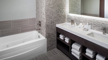 Un baño moderno con bañera, tocador doble y un espejo grande.
