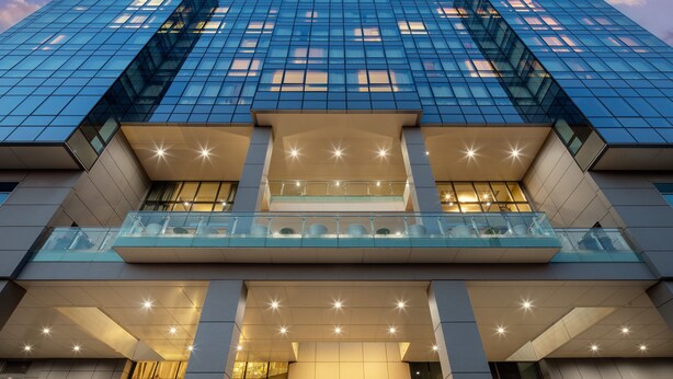 A modern high-rise building with a glass facade, multiple balconies, and a prominent entrance with illuminated star-like lights. - Hotel Indigo Flushing - LaGuardia by IHG (Flushing)