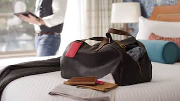 A bed with a black bag, a brown wallet, and a red card on it.