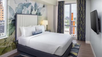 Ett modernt hotellrum med en stor säng, utsikt över staden och en platt-TV.