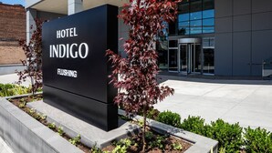 A modern hotel sign with the name "Hotel Indigo Flinging" and a revolving door. - Hotel Indigo Flushing - LaGuardia by IHG (Flushing)