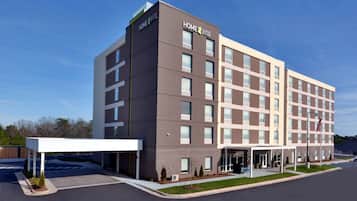 Home 2 Suites by Hilton offers a welcoming entrance with a small garden and a flagpole.
