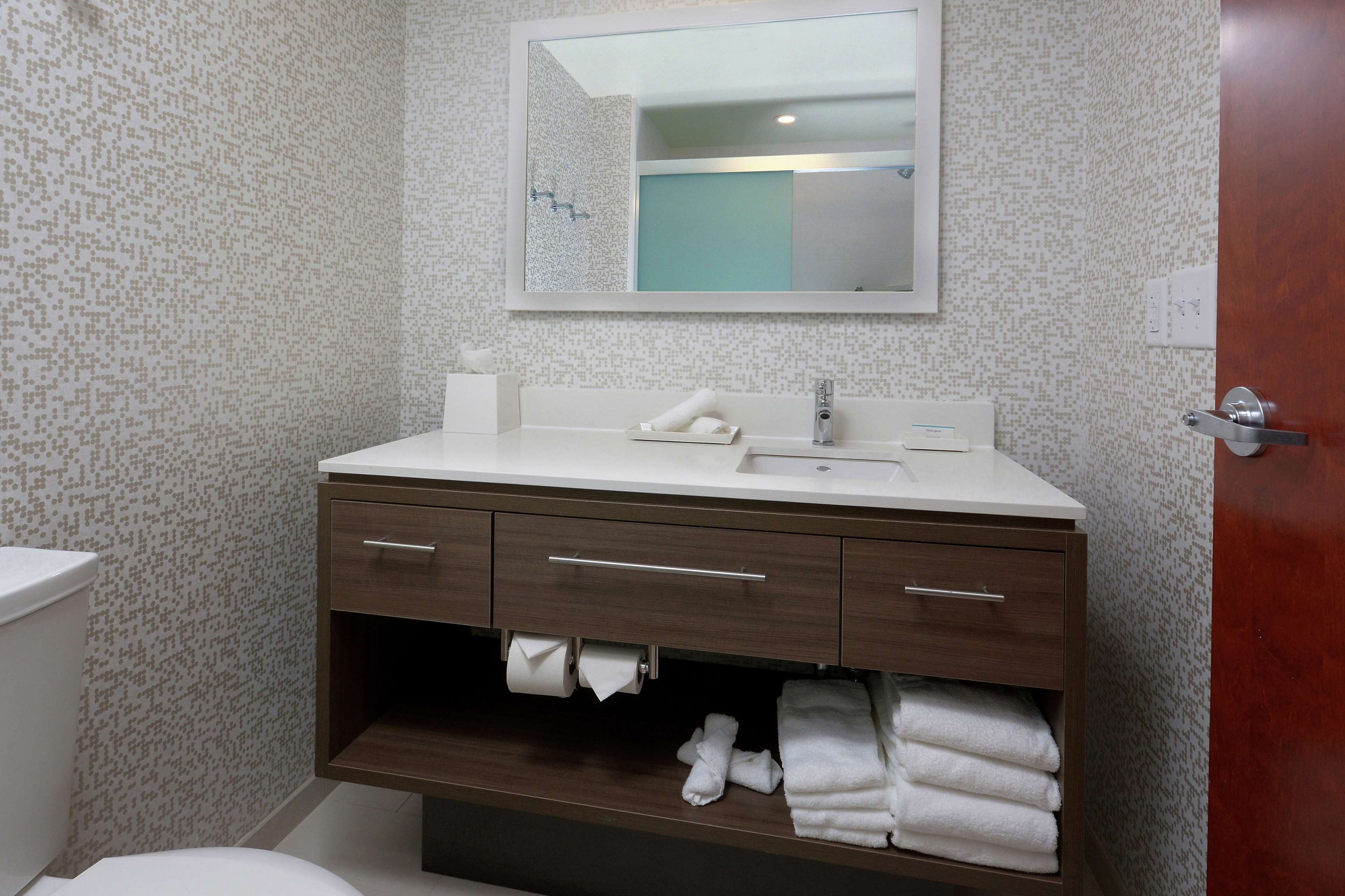 A bathroom with a white sink, dark wooden vanity, and a mirror above it.
