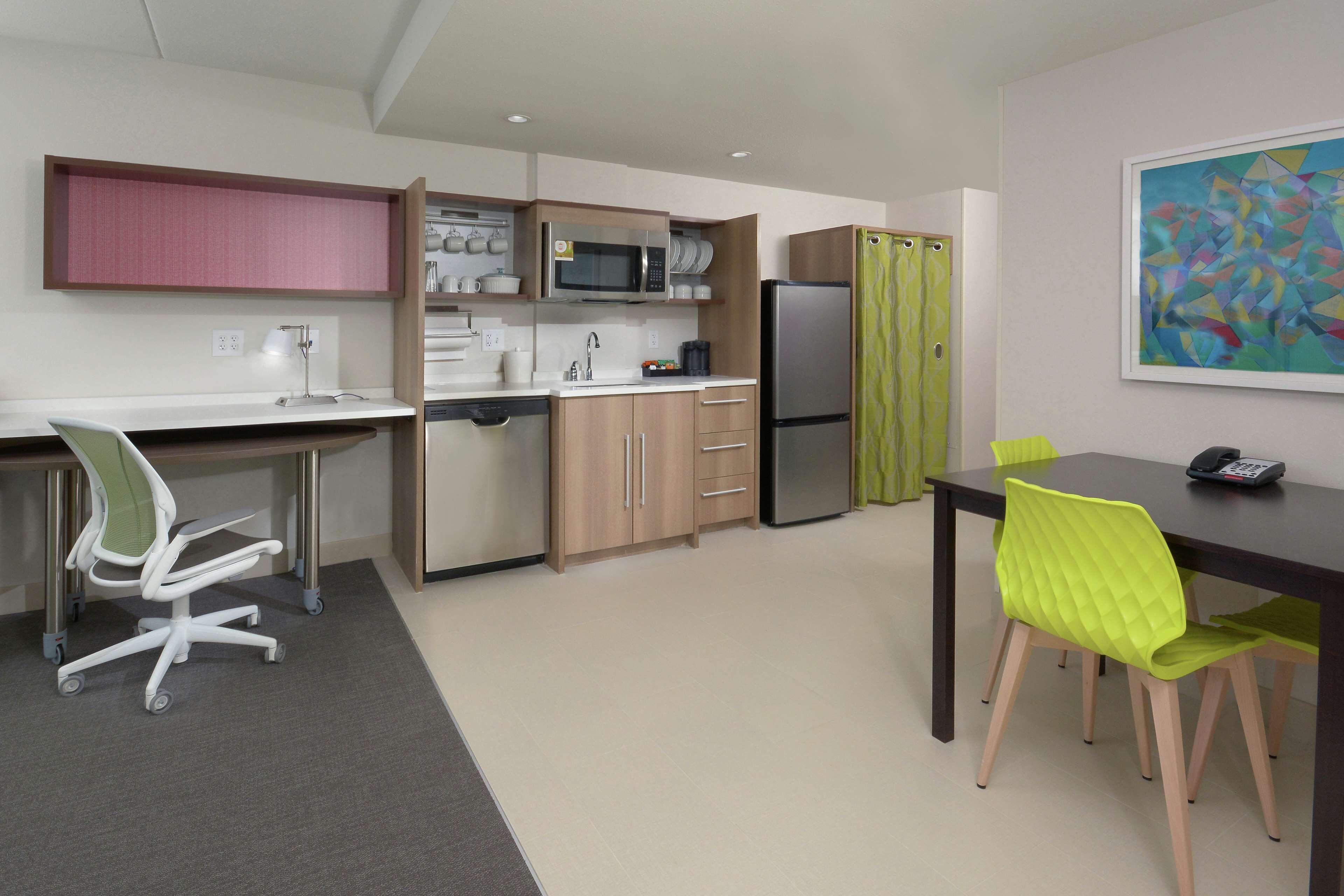 A modern kitchen with a microwave, refrigerator, and dining area with chairs and a table.