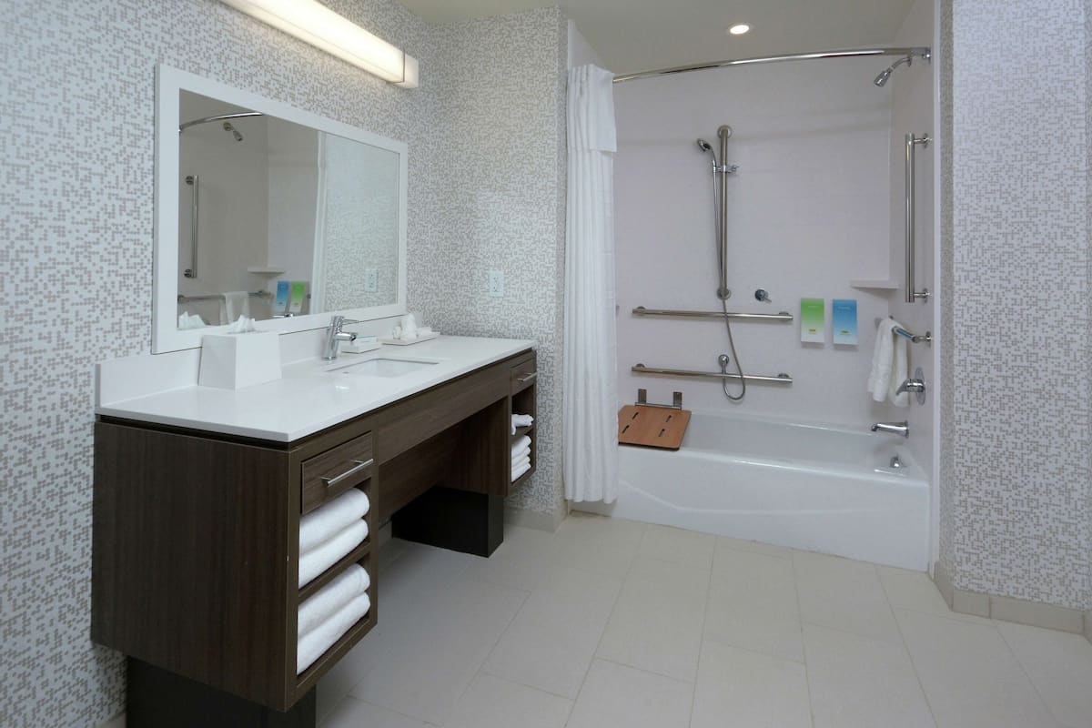 A modern bathroom with a double sink vanity, a large mirror, a walk-in shower, and a bathtub.