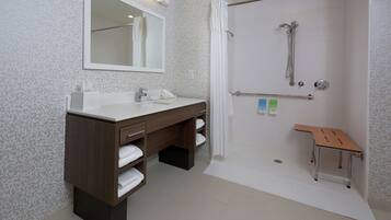 A bathroom with a shower, a sink with a mirror, and a bench.