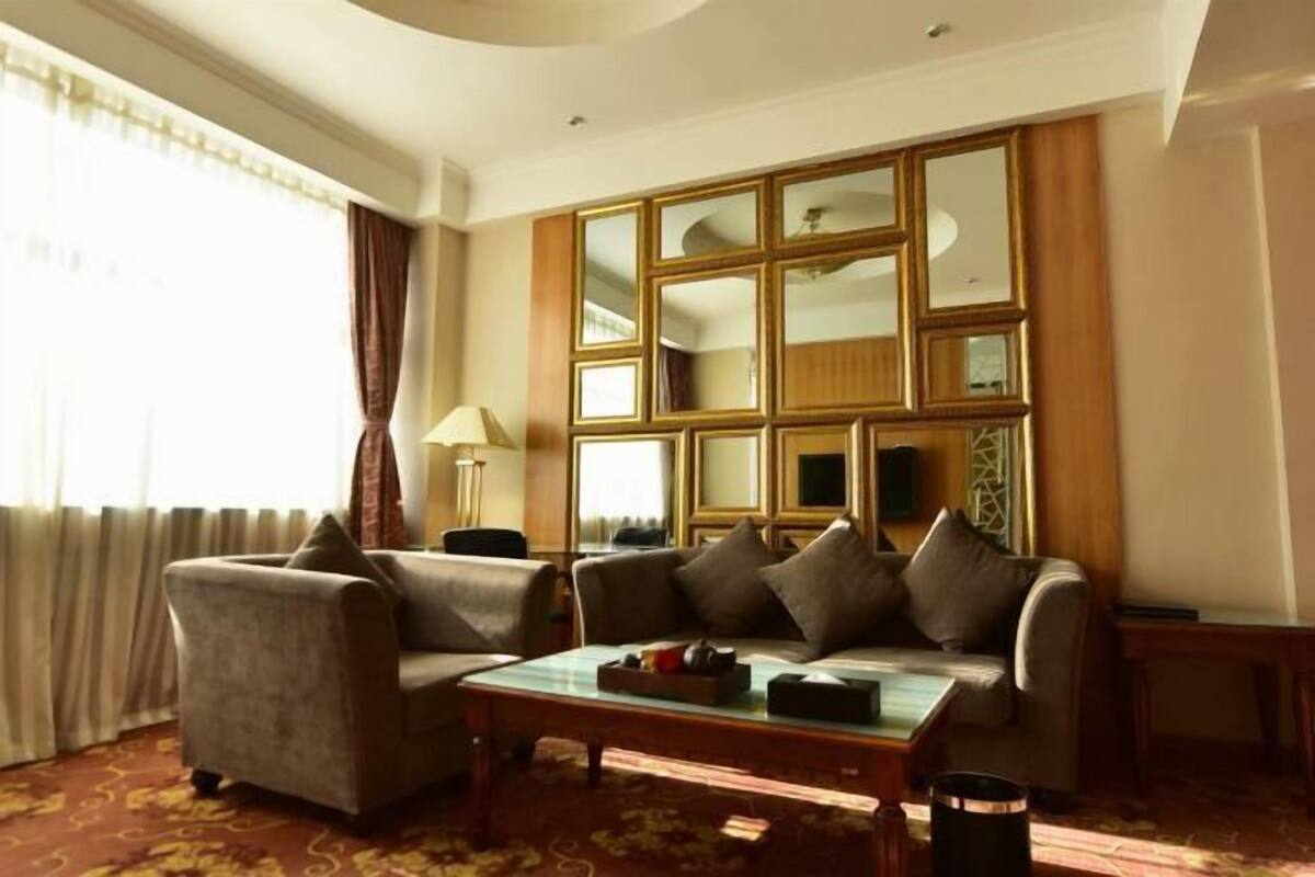 A living room with a sofa, a coffee table, and a large mirror with multiple panels.