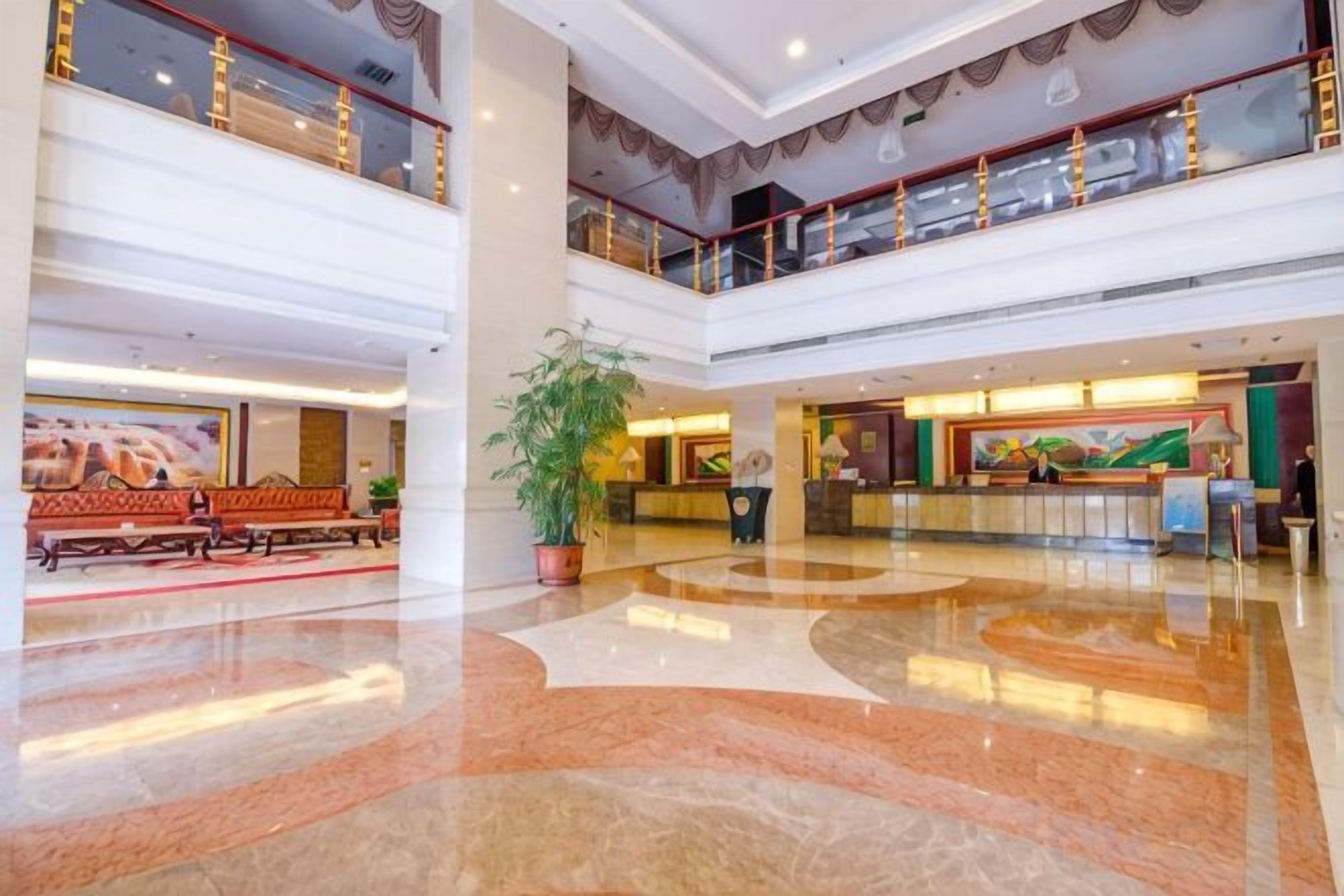 A spacious lobby with a reception desk, seating area, and a large potted plant.