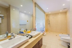 Un baño moderno con dos lavabos, un espejo grande, ducha e inodoro.