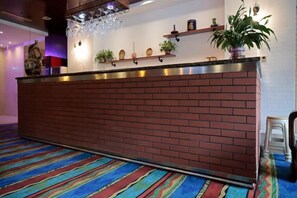 Una recepción con fachada de ladrillo, una alfombra colorida a rayas y una planta en el mostrador.