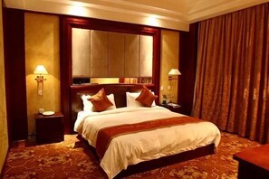 A hotel room with a large bed, two bedside tables, a nightstand, a mirror, and a curtain. - Tianlong Hotel (Baotou)