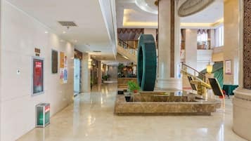 A spacious lobby with a central fountain, a staircase, and a large column.