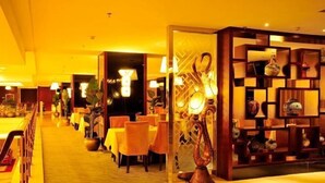 A hotel lobby with a warm yellow lighting, a reception desk, and a decorative wall with shelves. - Tianlong Hotel (Baotou)