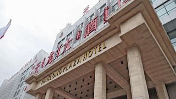 Fachada de hotel com grandes colunas, entrada imponente e sinalização indicando o nome 'THAI LONG PLAZA HOTEL'.