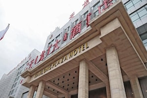 Fachada de hotel com grandes colunas, entrada imponente e sinalização indicando o nome 'THAI LONG PLAZA HOTEL'.