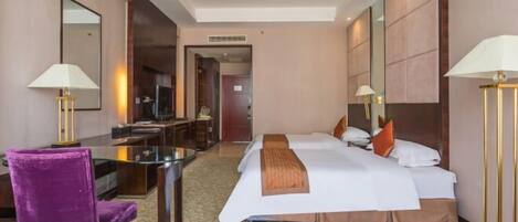 A hotel room with a bed, two bedside tables, a desk, a chair, and a sofa.
