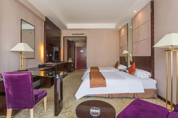 A hotel room with a bed, two bedside tables, a desk, a chair, and a sofa. - Tianlong Hotel (Baotou)
