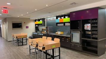 A modern kitchen area with a dining table and chairs, a microwave, and a refrigerator.