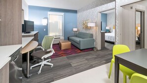 Een hotelkamer met een bureau, bureaustoel, bank en een bed.