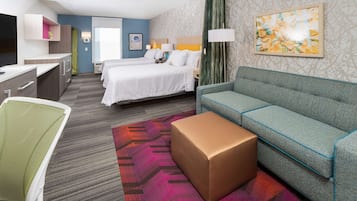 Hotelkamer met twee bedden, een bank, een bureau, een stoel en een kamerkleed met een patroon.