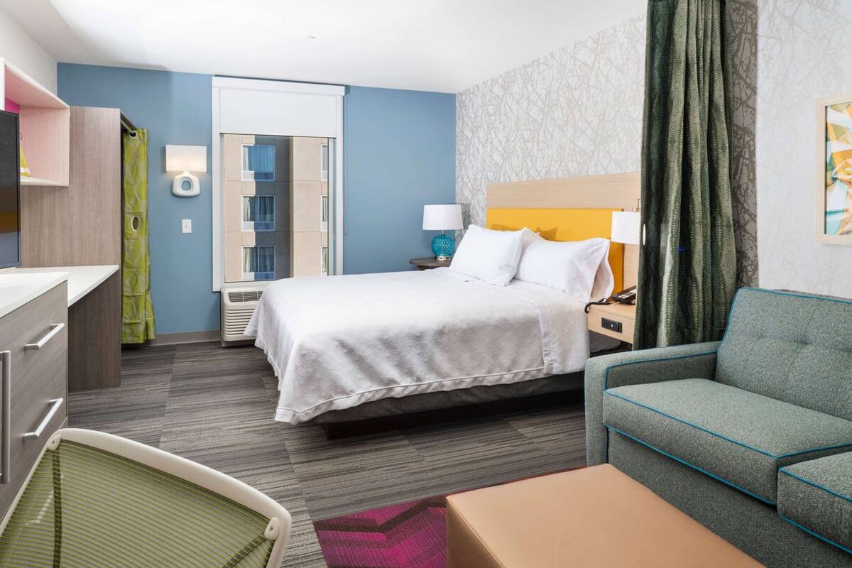 Une chambre d’hôtel avec un lit, un canapé, un bureau et une chaise.