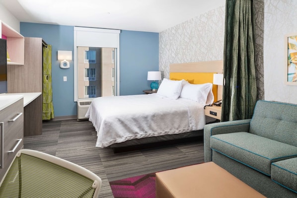 Una habitación de hotel con cama, sofá, escritorio y silla.