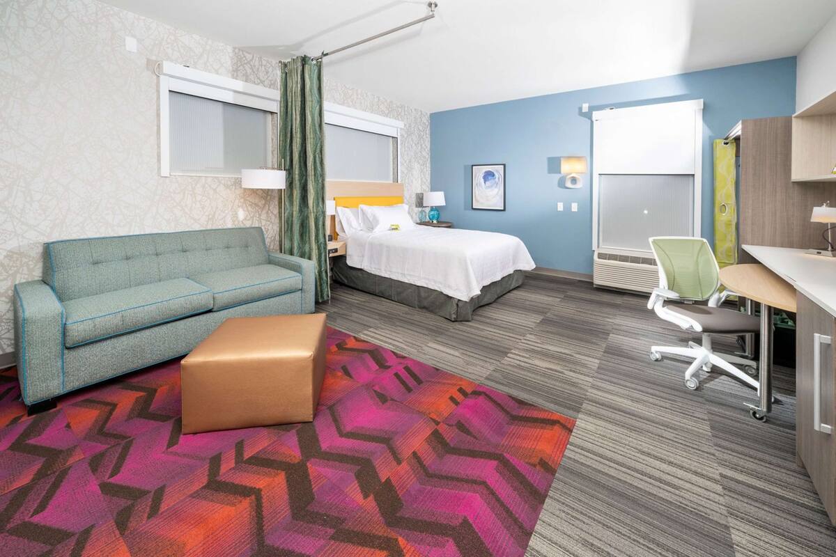 Une chambre d’hôtel avec un lit, un canapé, un bureau et une chaise.
