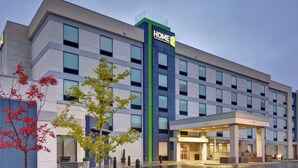 A modern hotel with a prominent "HOME 2" sign, a spacious entrance, and a well-maintained outdoor area with trees and a paved walkway. - Home2 Suites by Hilton Springdale (Springdale)