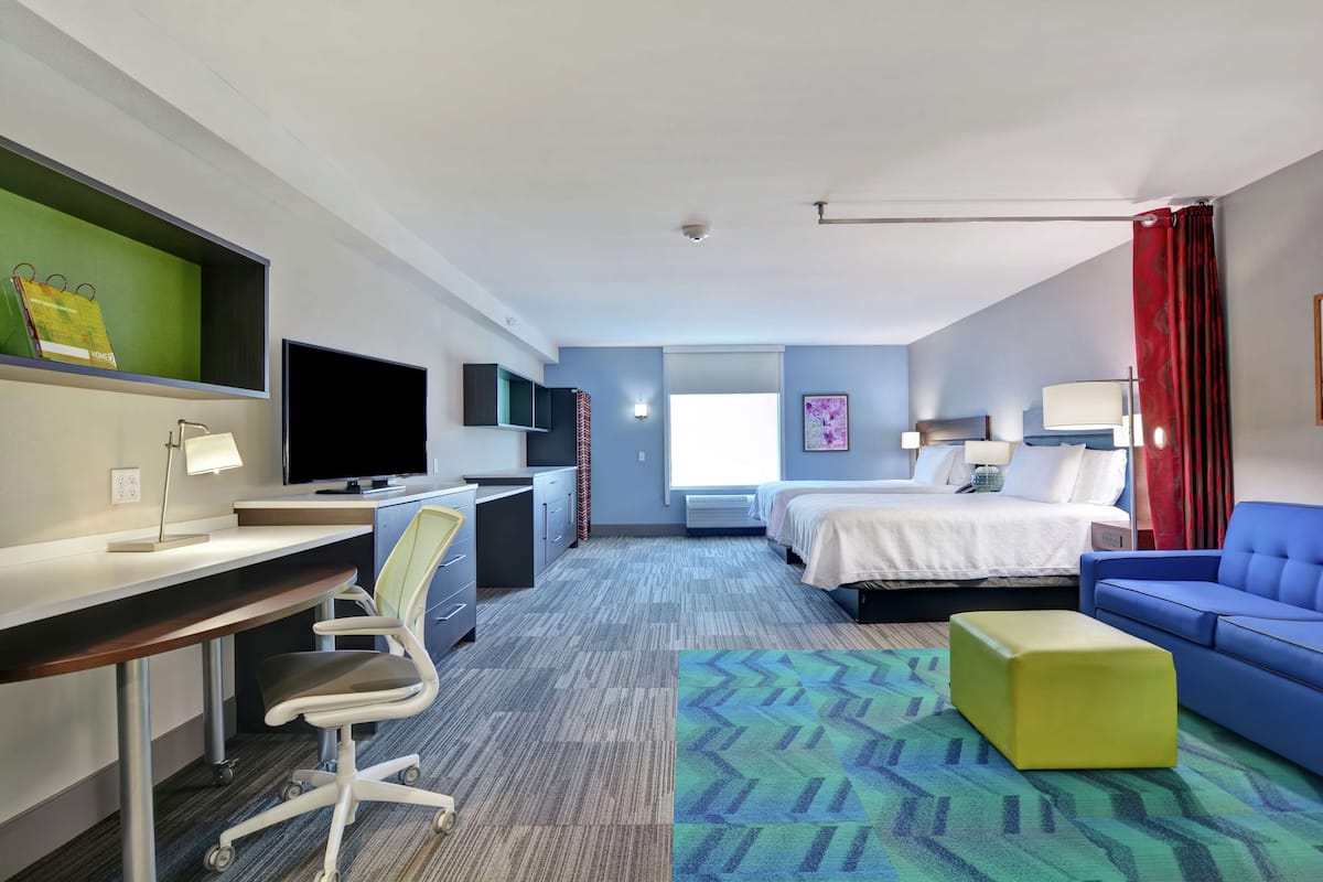 Ein Hotelzimmer mit Schreibtisch, Stuhl, Bett und einem blauen Sofa.