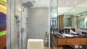 A modern bathroom with a glass-enclosed shower, a marble sink, and a large mirror.