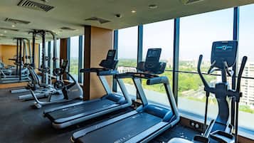 Un gimnasio con cintas de correr, elípticas y otros equipos de fitness.