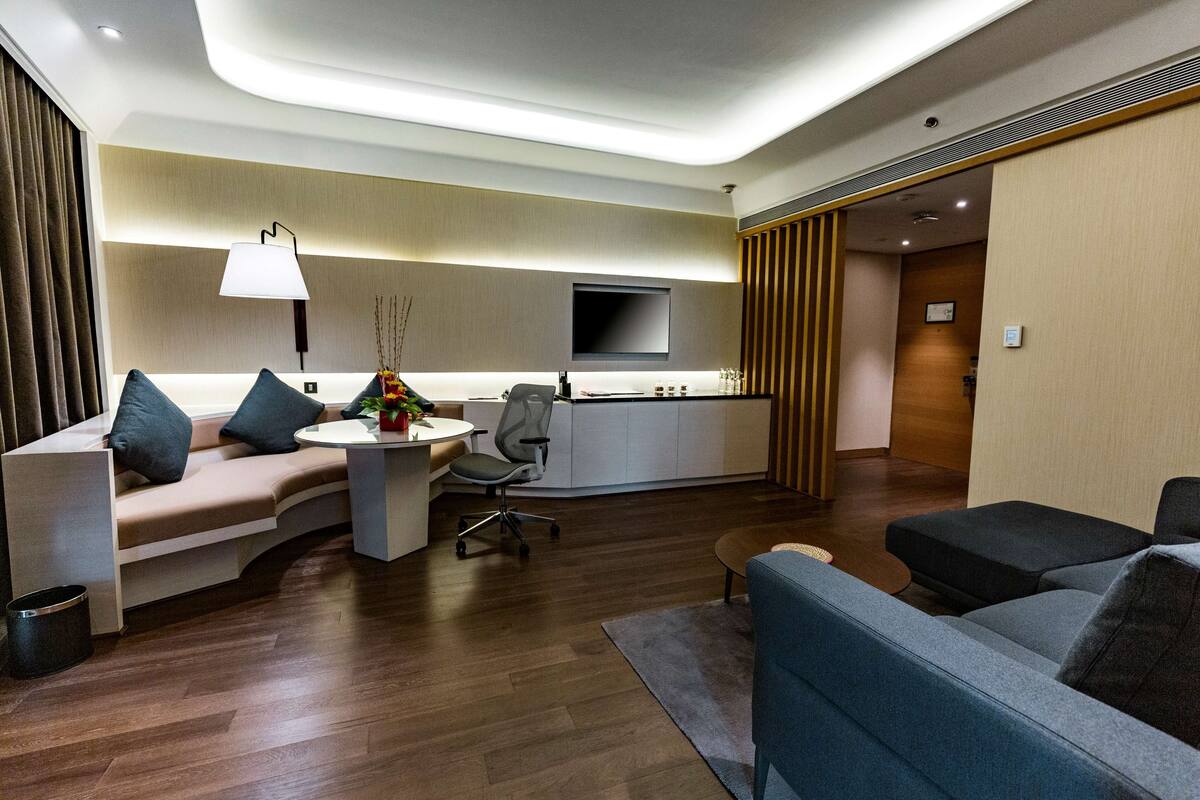 Un hall d’hôtel moderne avec un canapé, un fauteuil et une petite table sur laquelle se trouve une lampe.