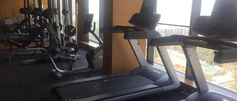 A gym with treadmills, weight machines, and a large window providing a view of the outdoors.