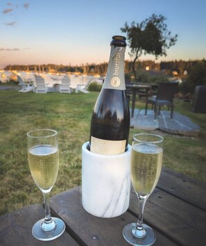A bottle of champagne in a marble holder with two glasses on a wooden table. - East Wind Inn on the Water (Tenants Harbor)