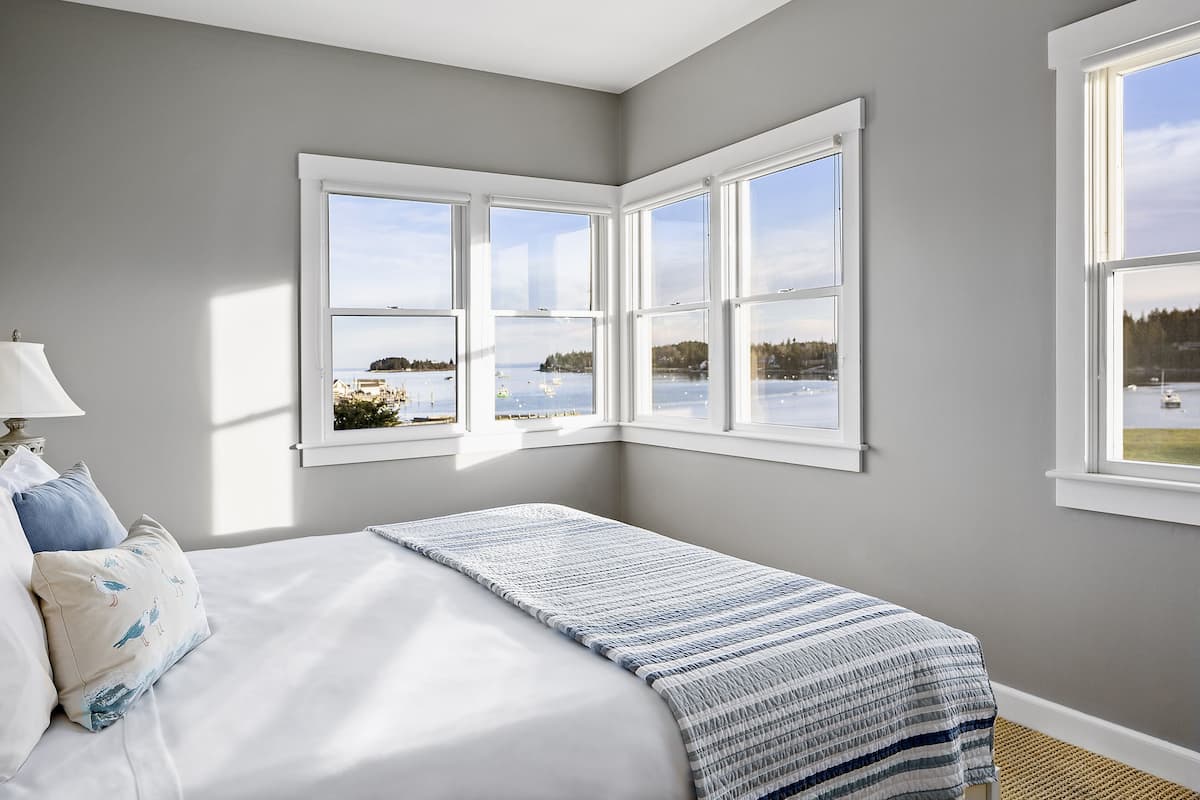 A bedroom with a bed, a window with a view of a lake, and a lamp.