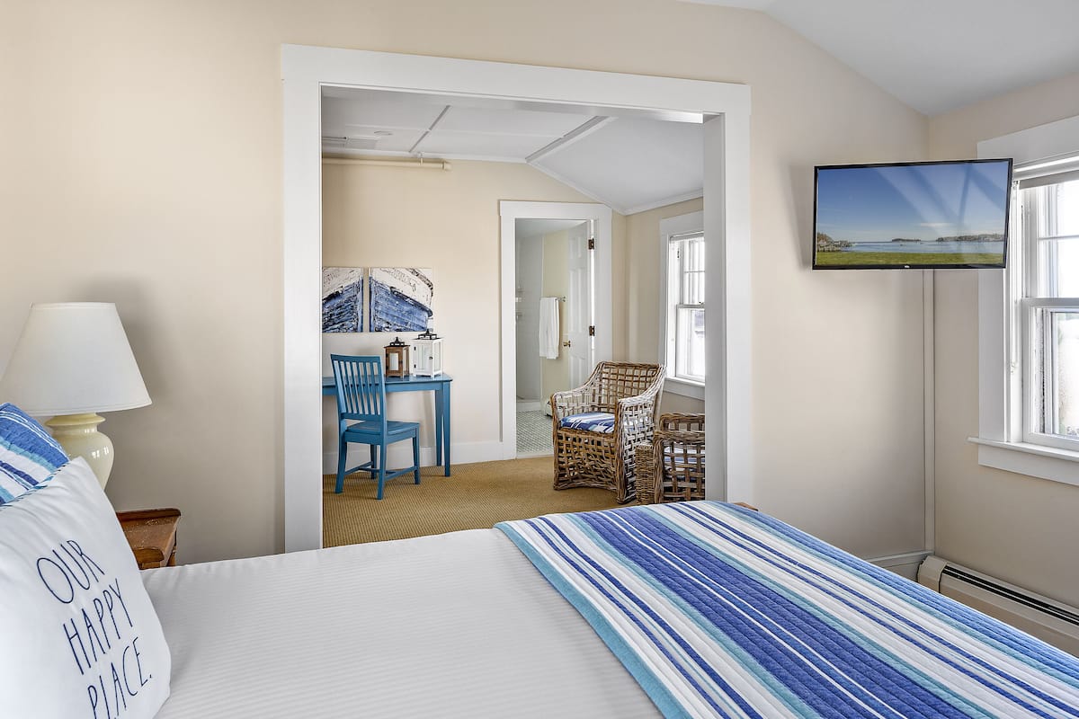 A hotel room with a bed, a desk, a chair, a television, and a window.
