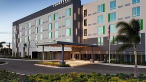 A Courtyard by Marriott hotel with a modern design, featuring a covered entrance and a landscaped area with palm trees. - Courtyard by Marriott Winter Haven (Winter Haven)