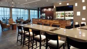 A modern hotel lobby with a long reception desk, bar area, and seating arrangement. - Courtyard by Marriott Winter Haven (Winter Haven)