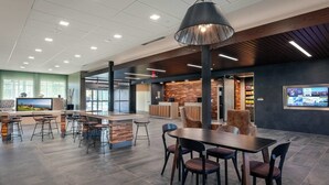 A spacious indoor area with a bar, seating arrangements, and a large screen displaying content. - Courtyard by Marriott Winter Haven (Winter Haven)