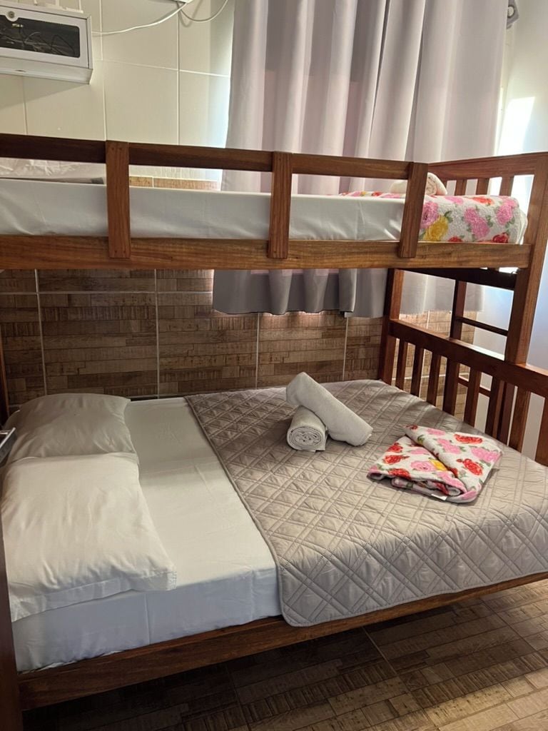Een stapelbed met een houten hoofdbord, een gewatteerde sprei en een bloemenkussen.