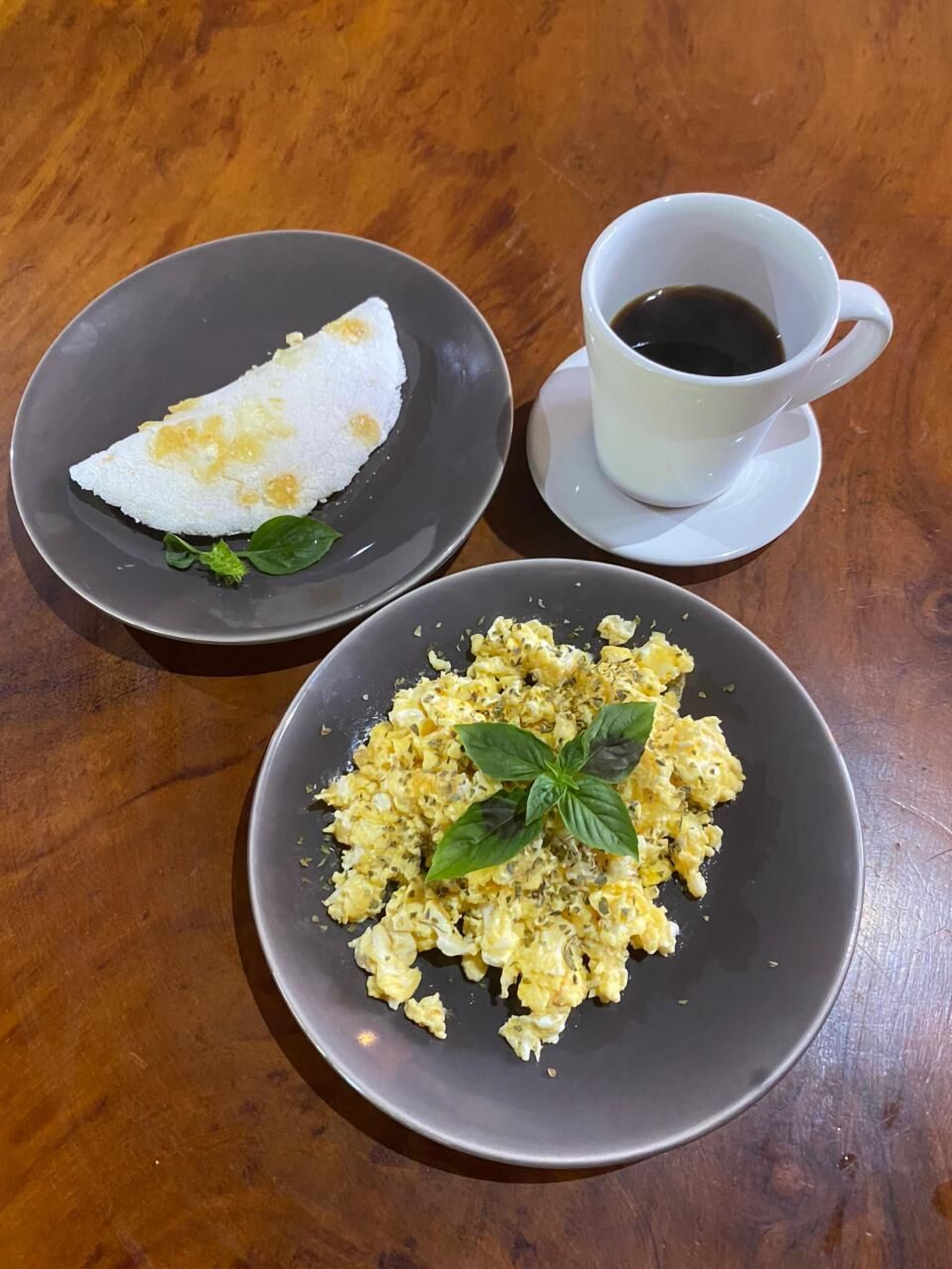 Two plates of food and a cup of coffee on a wooden table.